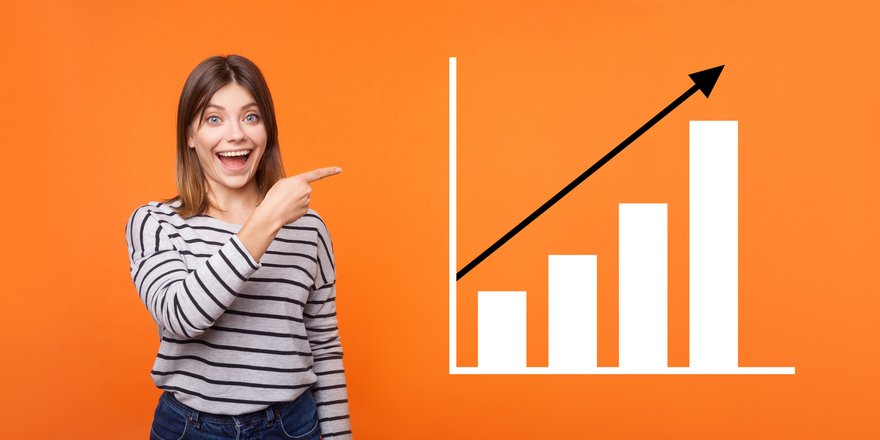 A happy person with a big smile on their face standing next to chart showing stock growth.